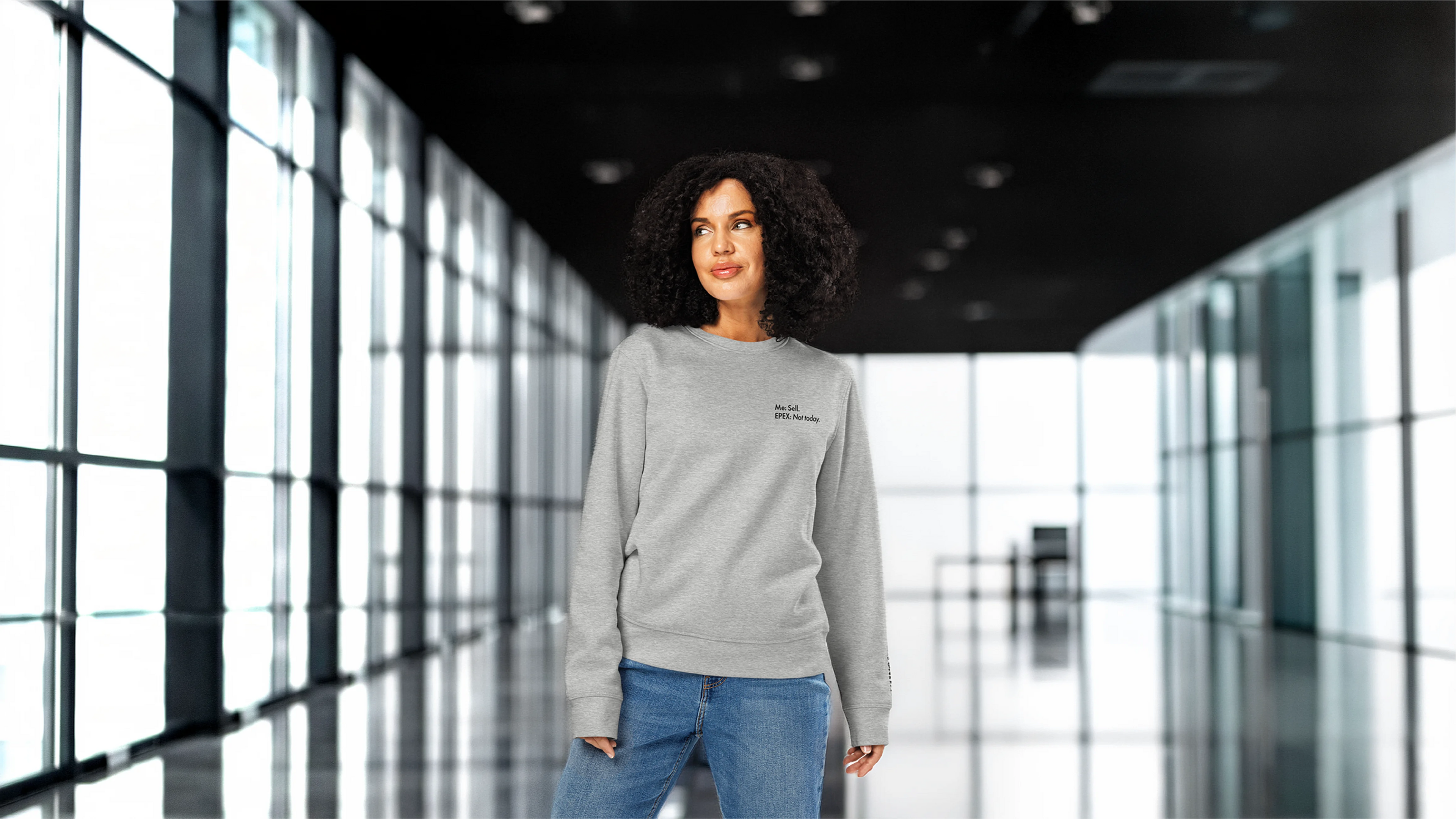 Woman wearing a gray sweatshirt with a logo in a modern building
