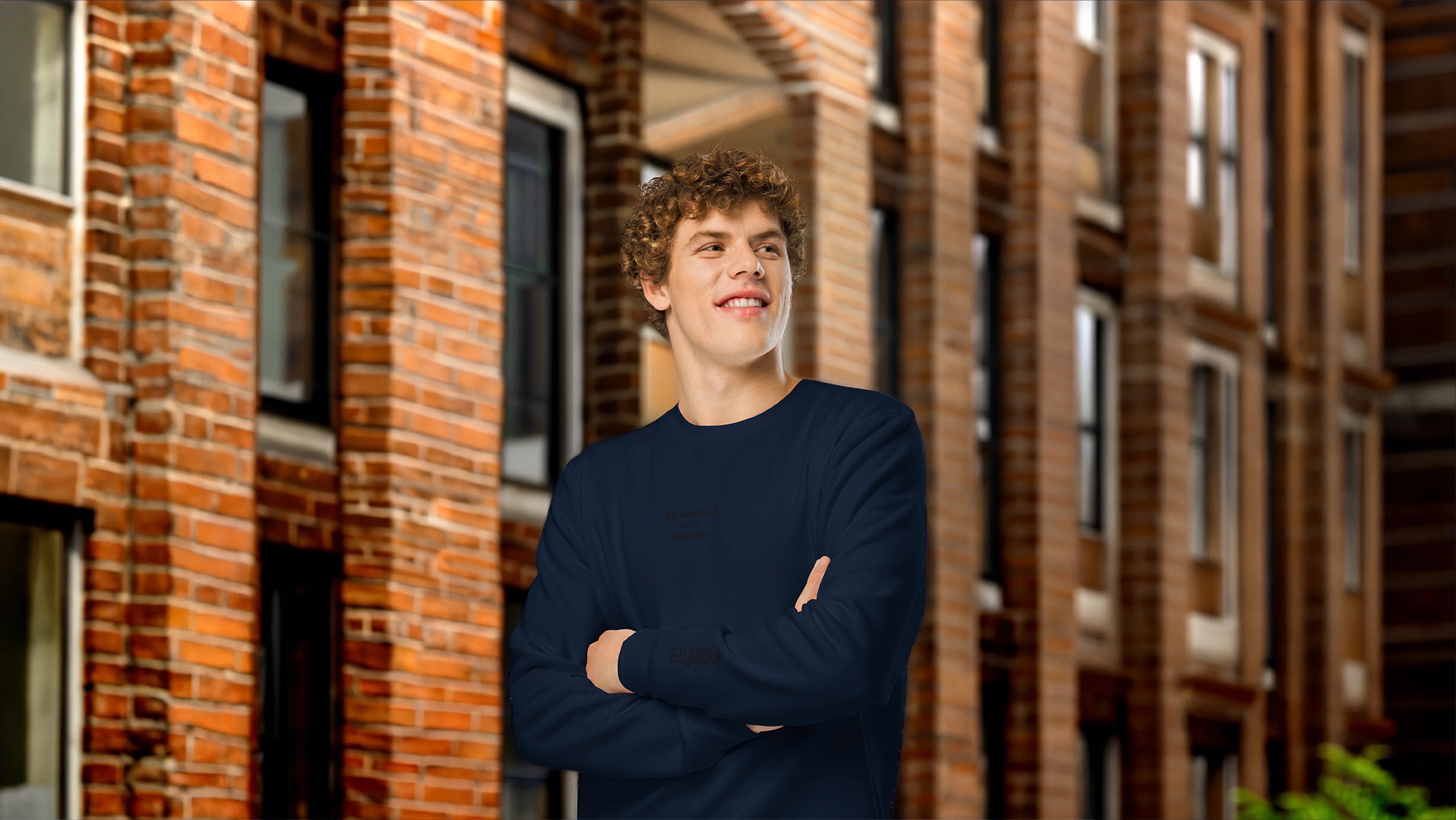 Man standing with arms crossed in front of a brick building